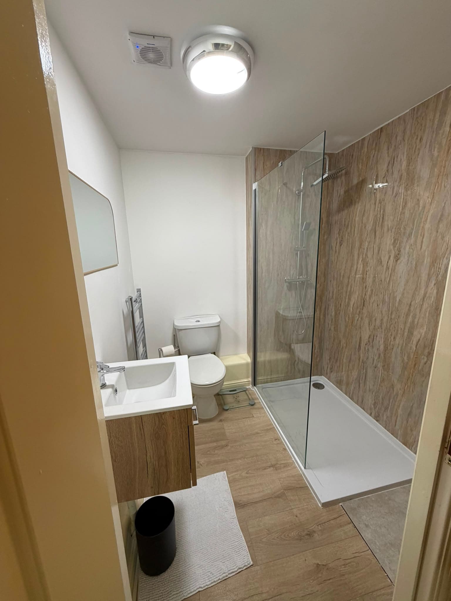 Walk-in shower room with wood-effect wall panels, glass screen and wall-hung vanity unit