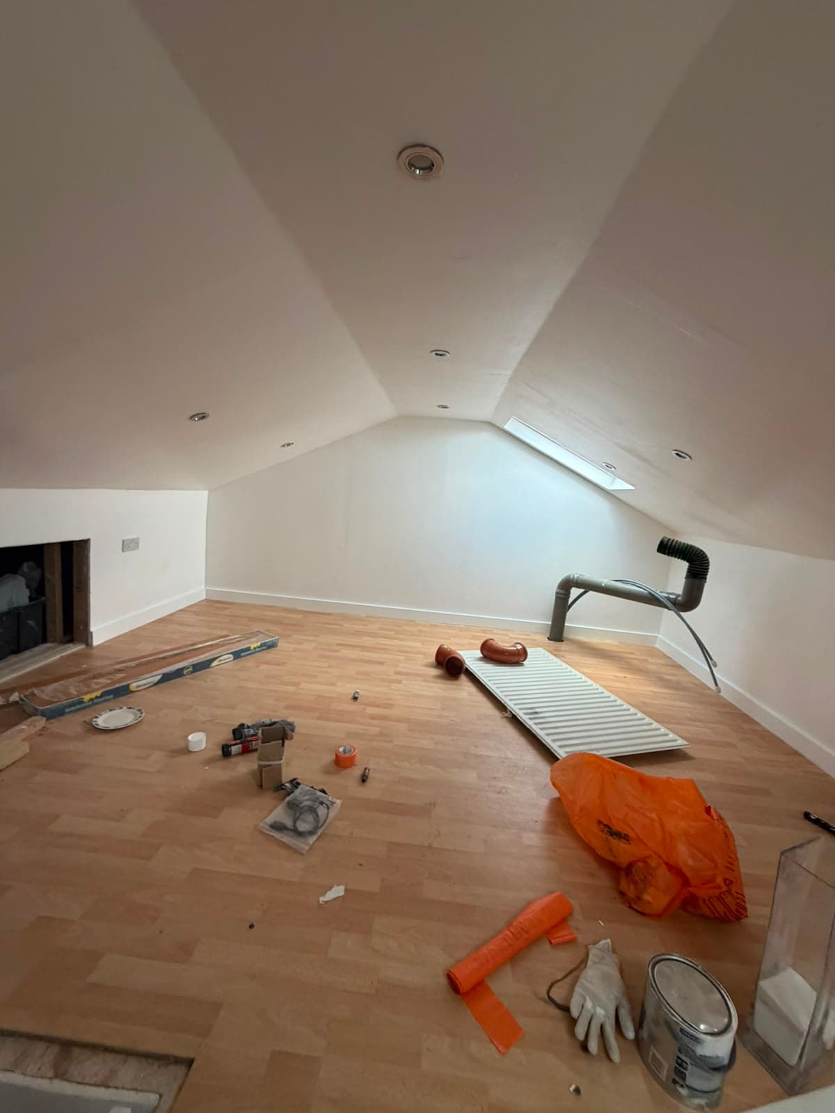 Converted loft room with sloped ceiling, roof window and recessed spotlights during fit-out